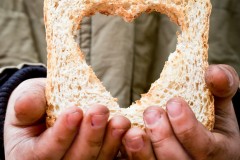 Helping the needy concept with dirty hands of a child holding slice of bread